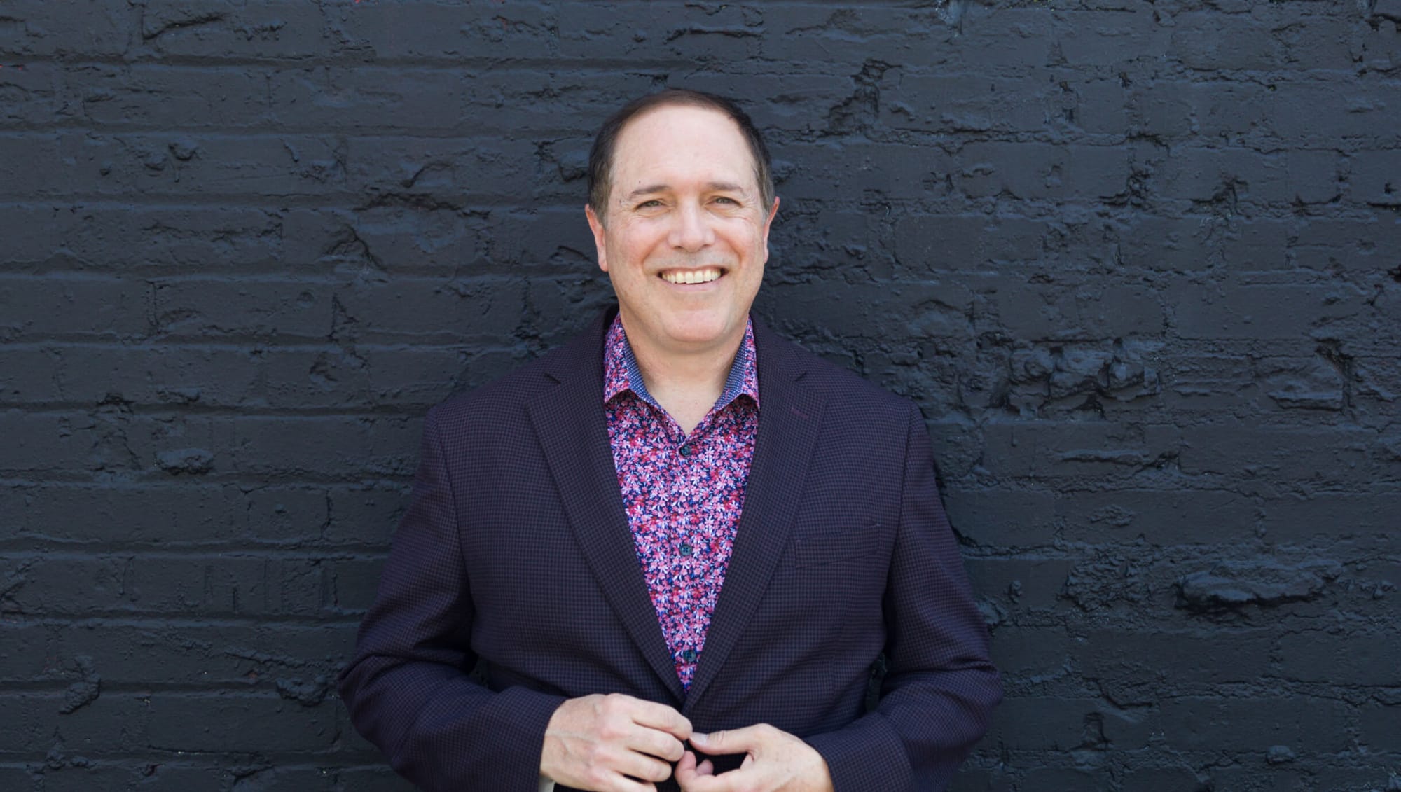 David Martinez magician standing in front of blue brick wall in San Francisco