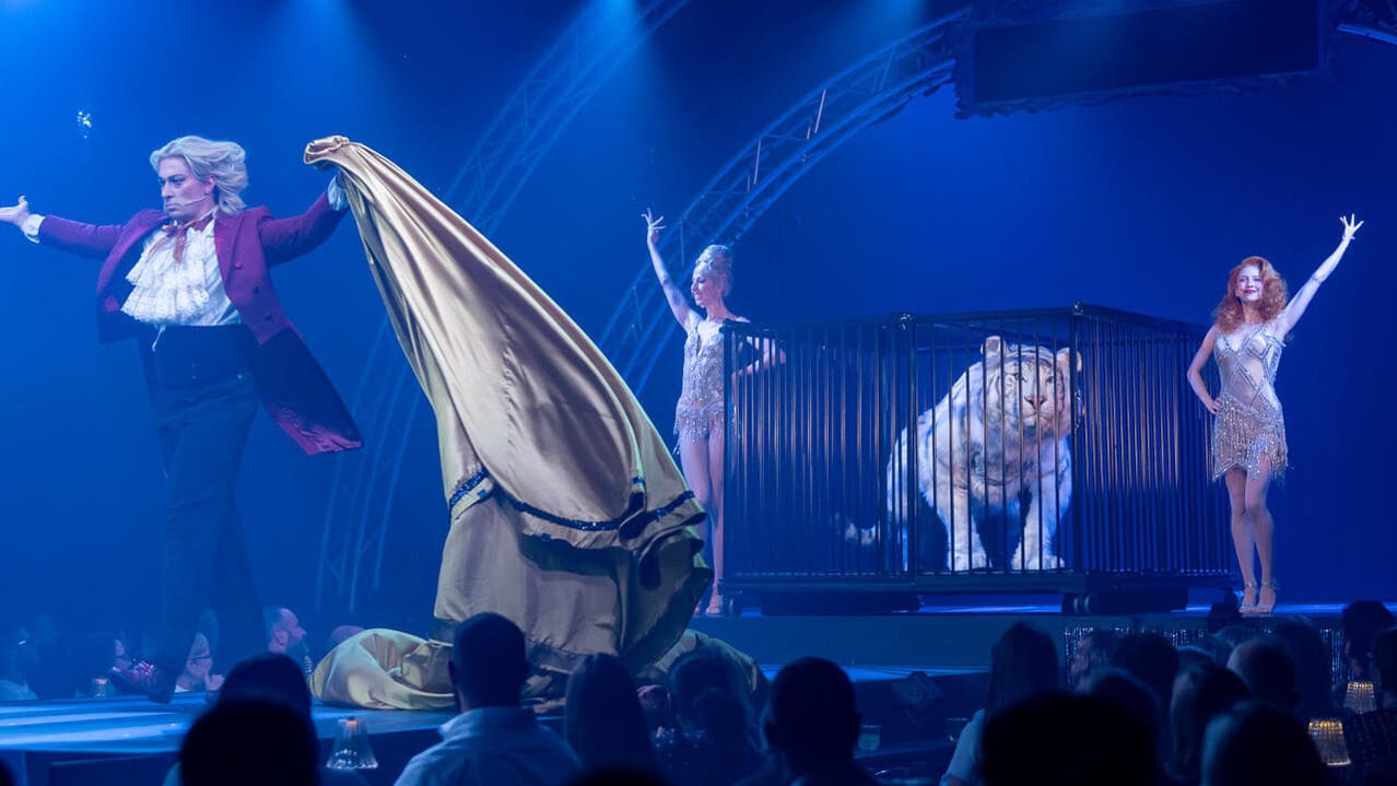 Image of actors on stage with puppet tiger in cage