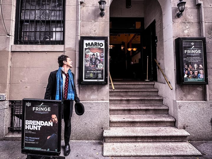 Mario the Maker Magician stood outside Soho Playhouse next to show poster