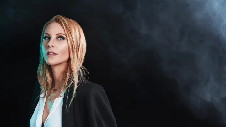 Magician Caroline Ravn in studio for headshot surrounded by smoke against black background