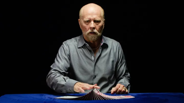 Magician Richard Turner glides his hand along a deck of cards spread out in front of him